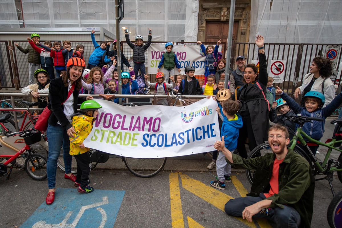 Bambini e genitori con lo striscione Vogliamo Strade Scolastiche durante Street for Kids